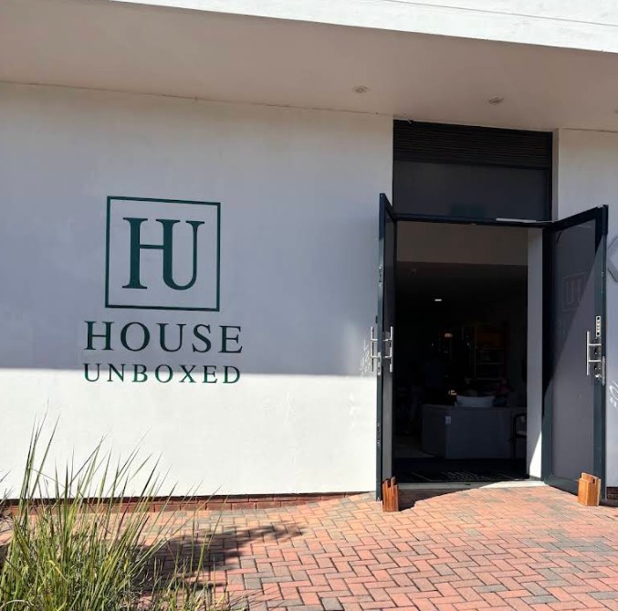Open glass doors below the House Unboxed logo painted on a white wall