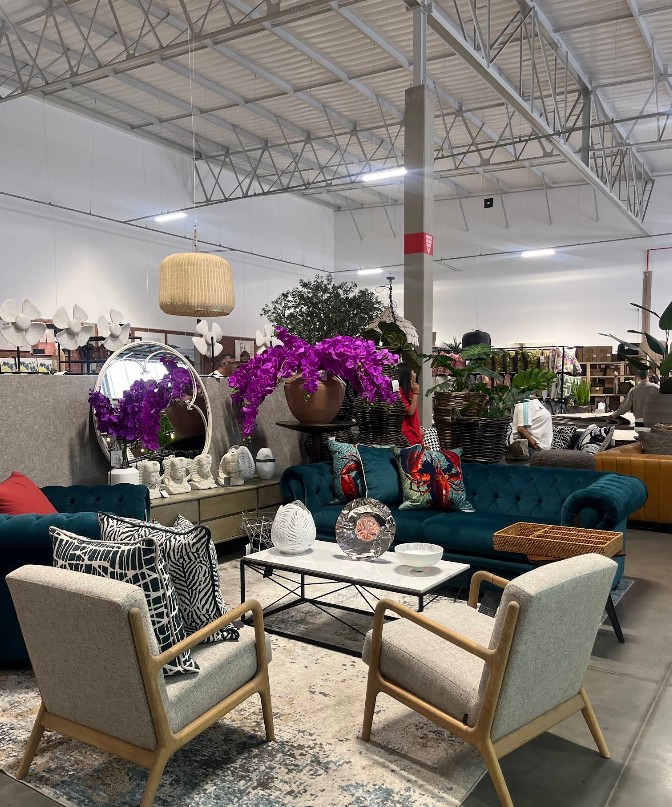 Teal buttoned sofas styled with patterned scatter cushions, a round mirror and large planters