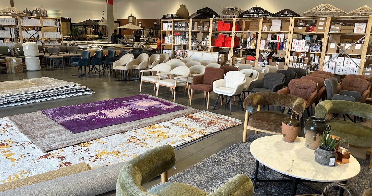 Rows of dining and occasional chairs beside stacks of designer rugs