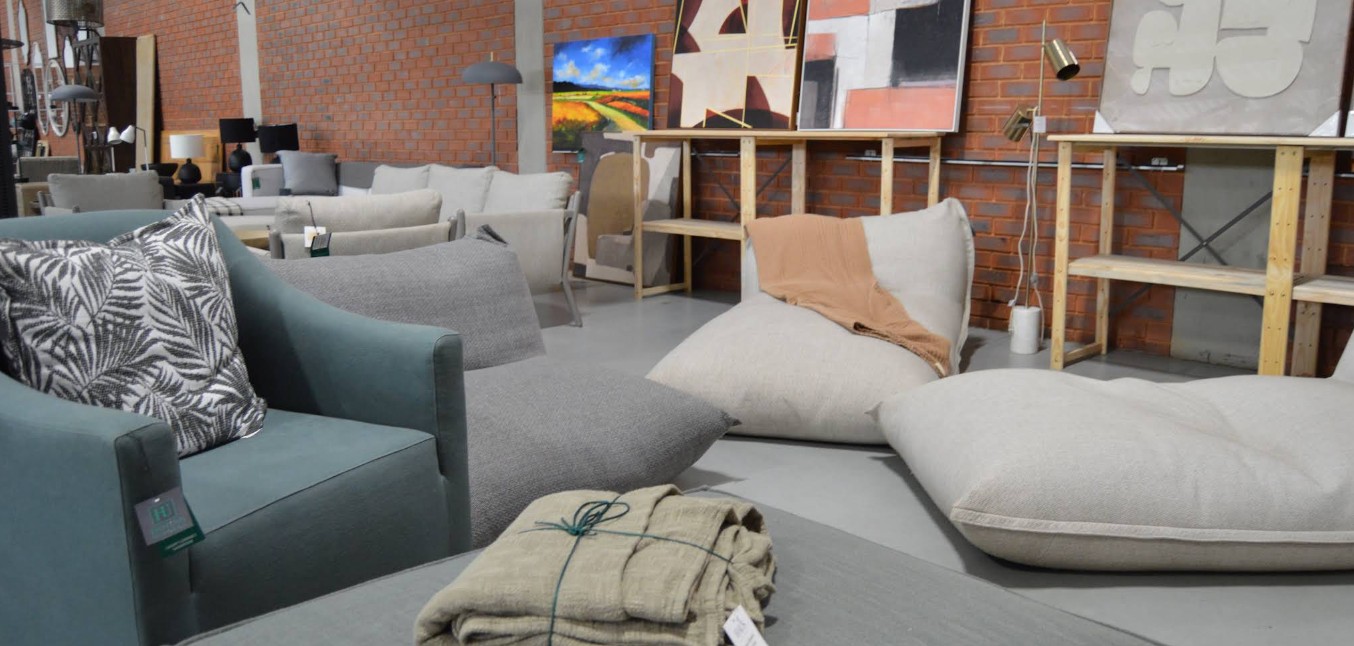 Upholstered armchairs and oversized floor cushions in front of framed artwork