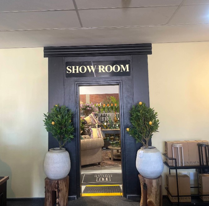 Black showroom doorway framed by potted lemon trees, with décor visible inside